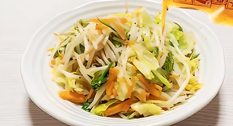 野菜炒めに納豆のタレをかける様子