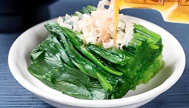 ほうれん草のおひたしに納豆のタレをかける様子