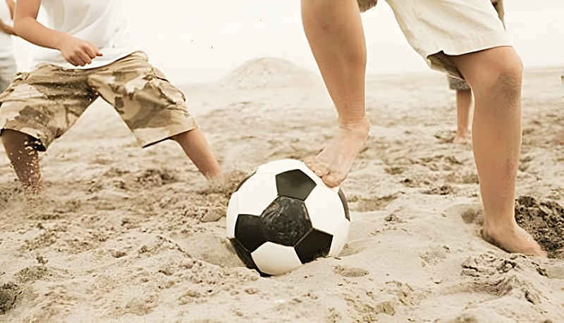 砂浜でサッカーをする人達